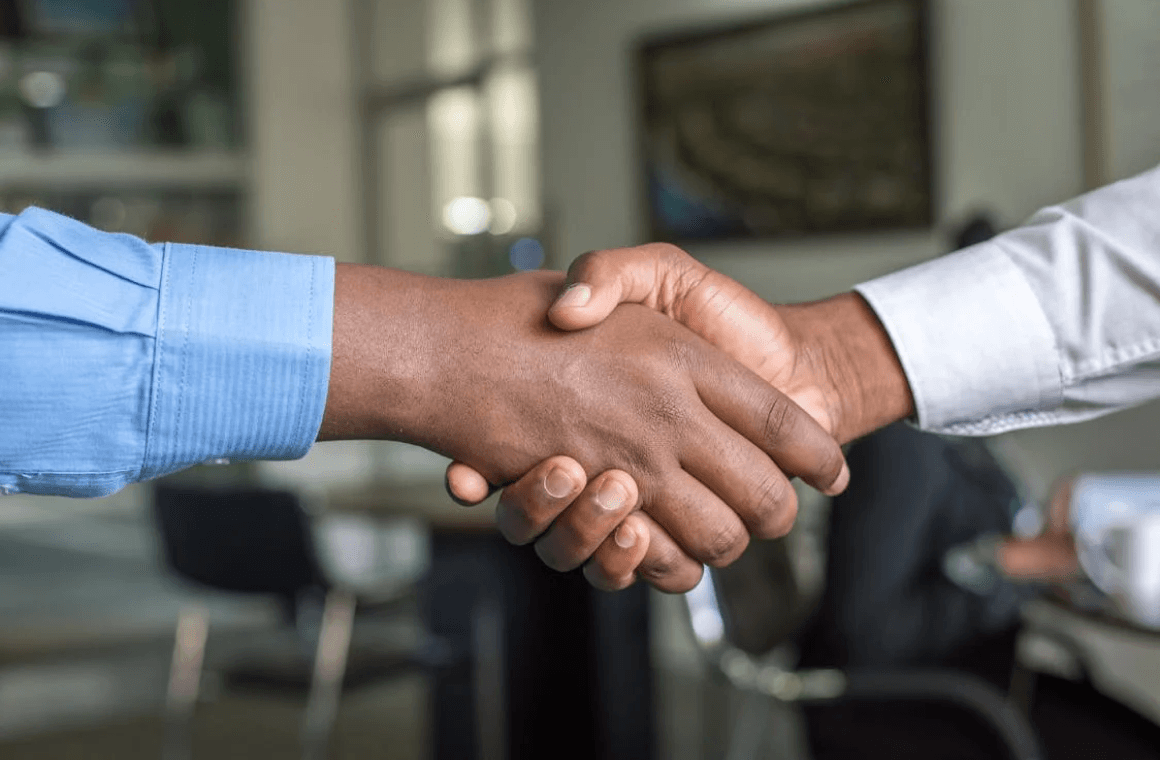 two hands shaking with an office background